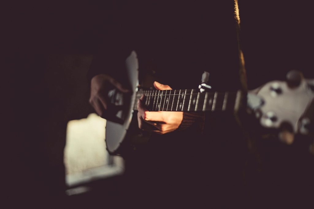 Hands on the fretboard of a stringed instrument in low, warm light