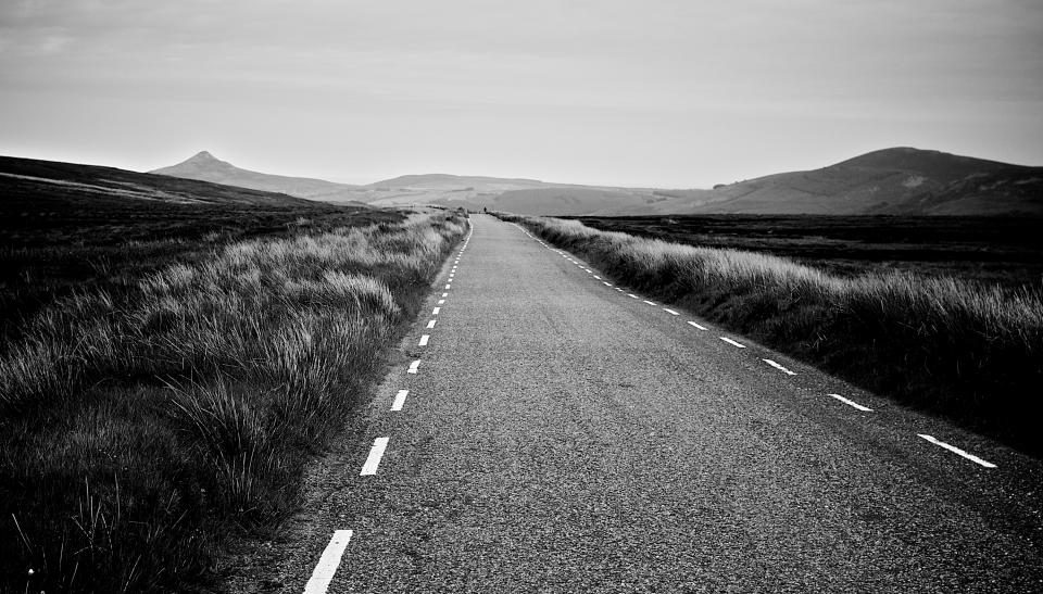 An empty two-lane road running out through open country