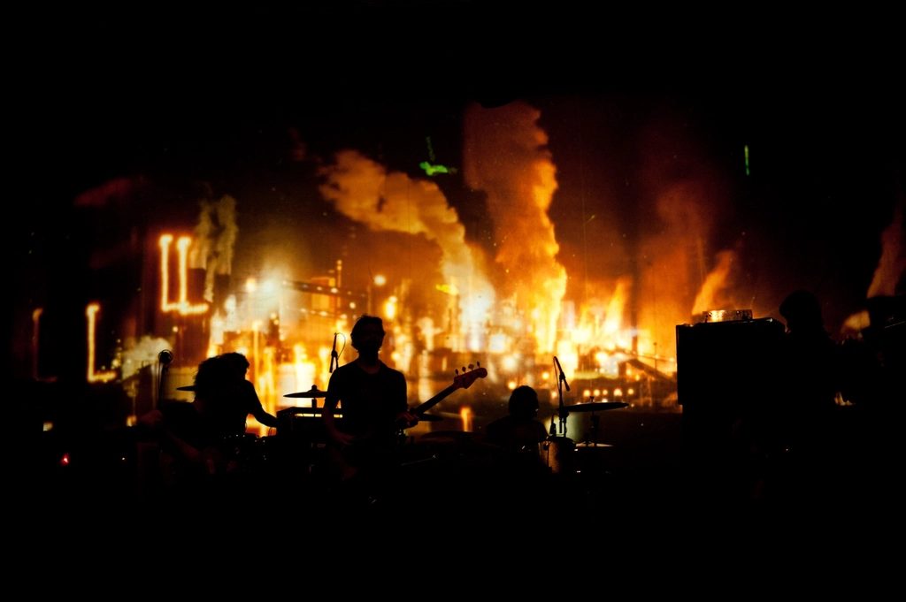 A band playing in silhouette against warm stage light